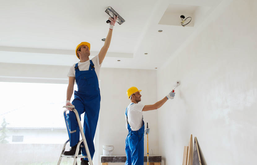 Two people working on drywall in a home