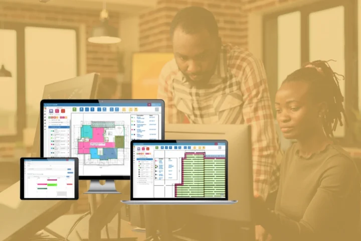Two people working at a desk with multiple screens displaying construction estimating software and project management tools.