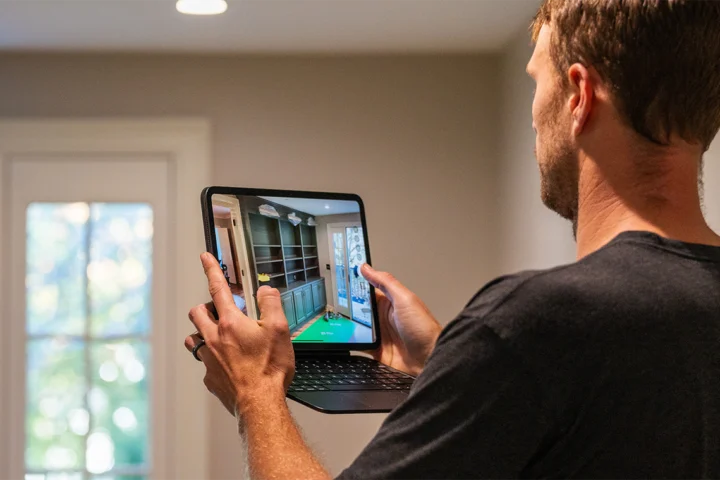 Construction professional using a tablet to review and document project details during a home walkthrough.